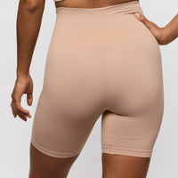 Beige shapewear shorts worn by a person on a plain background