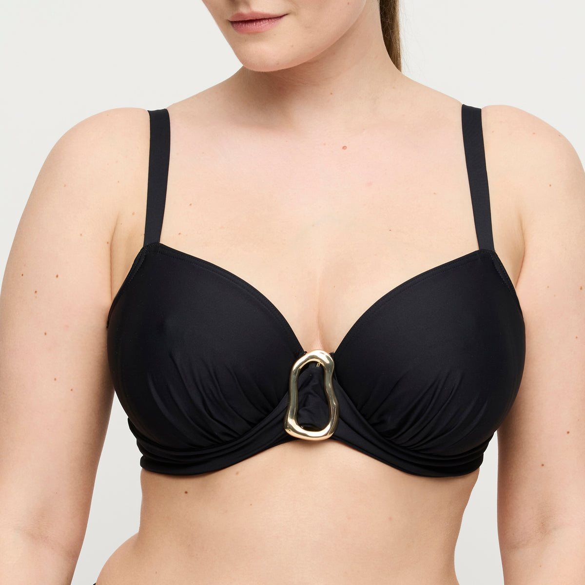Black bikini top with a gold buckle on a neutral background