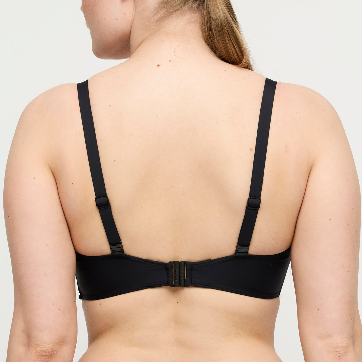 Black bra worn by a person on a plain background