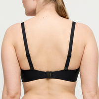 Black bra worn by a person on a plain background