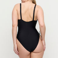 Black swimsuit worn by a person on a white background
