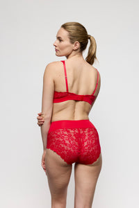 Woman wearing a red lace lingerie set on a plain background