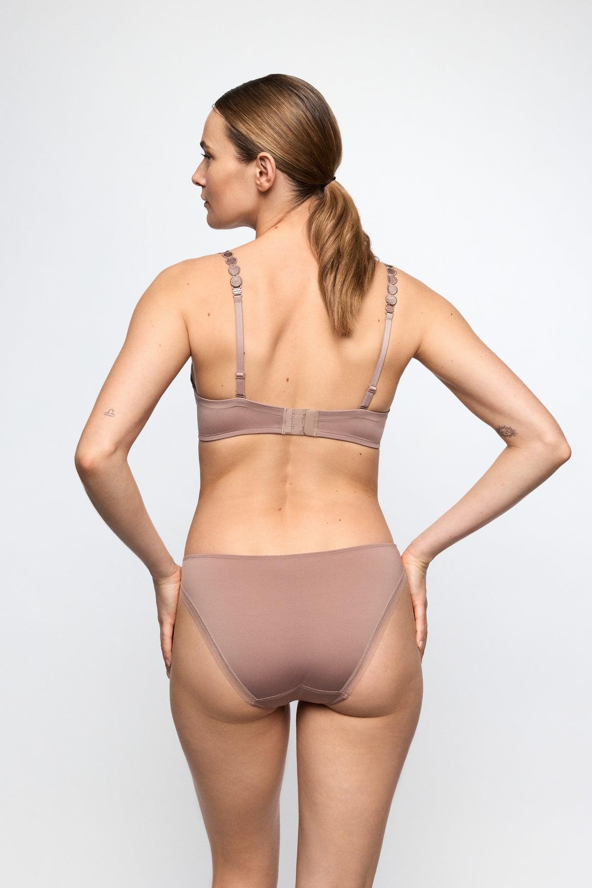 Woman wearing a beige bra and panties set on a white background