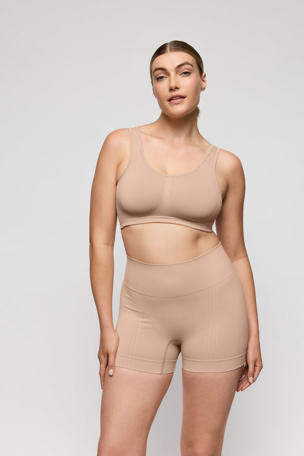 Woman wearing a beige shapewear set on a light gray background