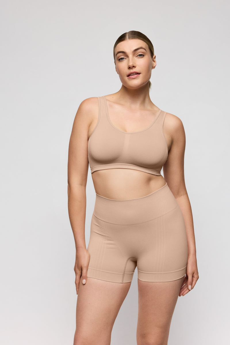 Woman wearing a beige shapewear set on a light gray background