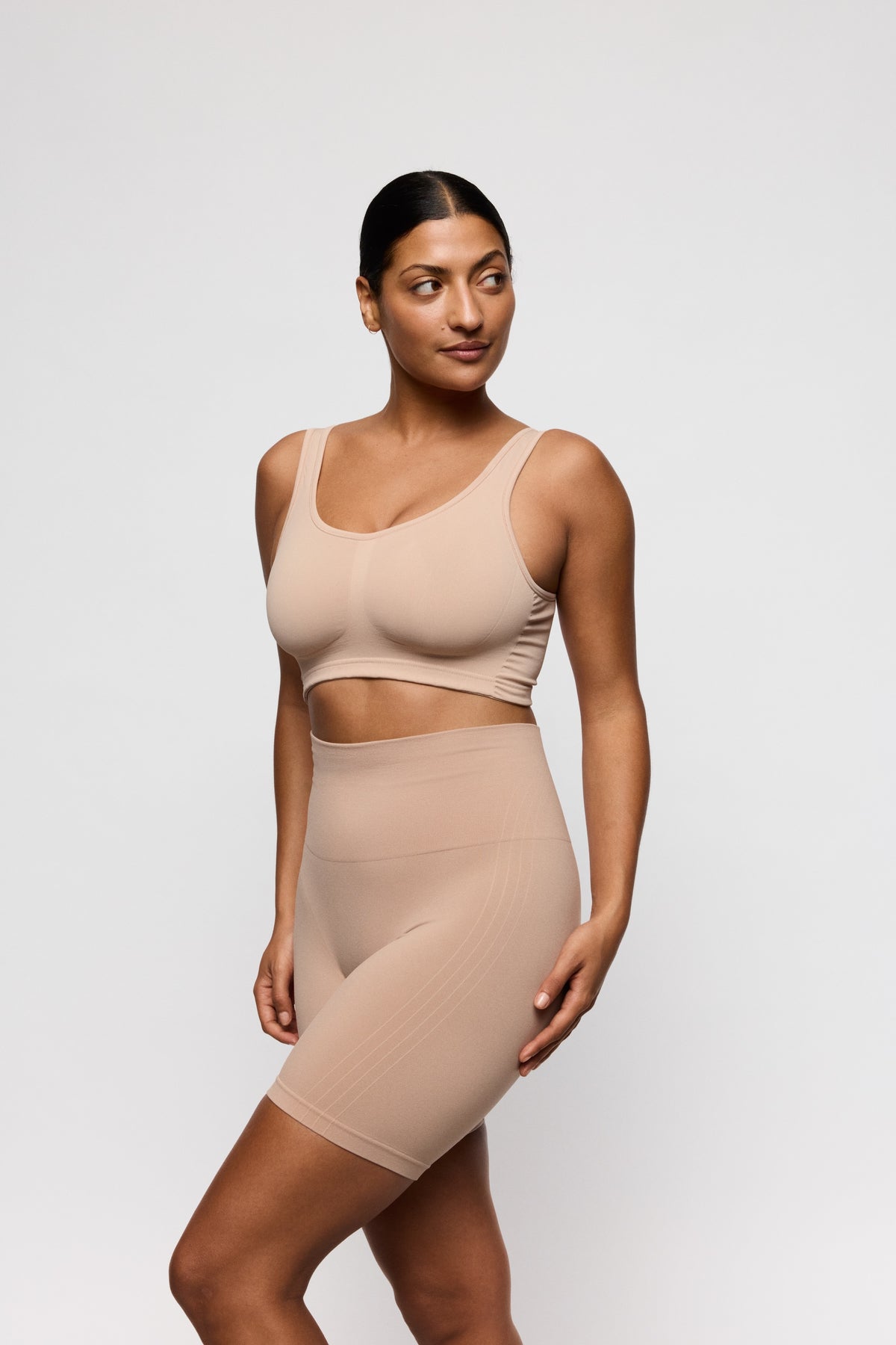 Woman wearing a beige shapewear outfit on a white background