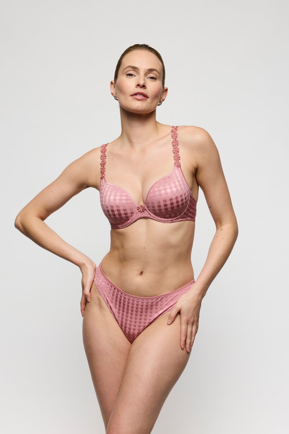 Woman wearing a pink lingerie set against a plain background