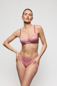 Woman wearing a pink lingerie set against a plain background