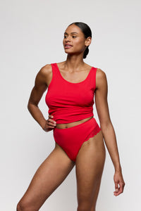 Woman wearing a red thong and red top against a white background