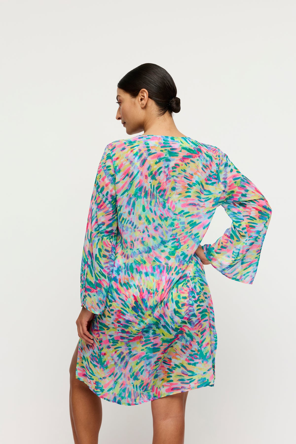 Woman wearing a colorful dress with long sleeves on a white background