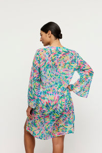 Woman wearing a colorful dress with long sleeves on a white background