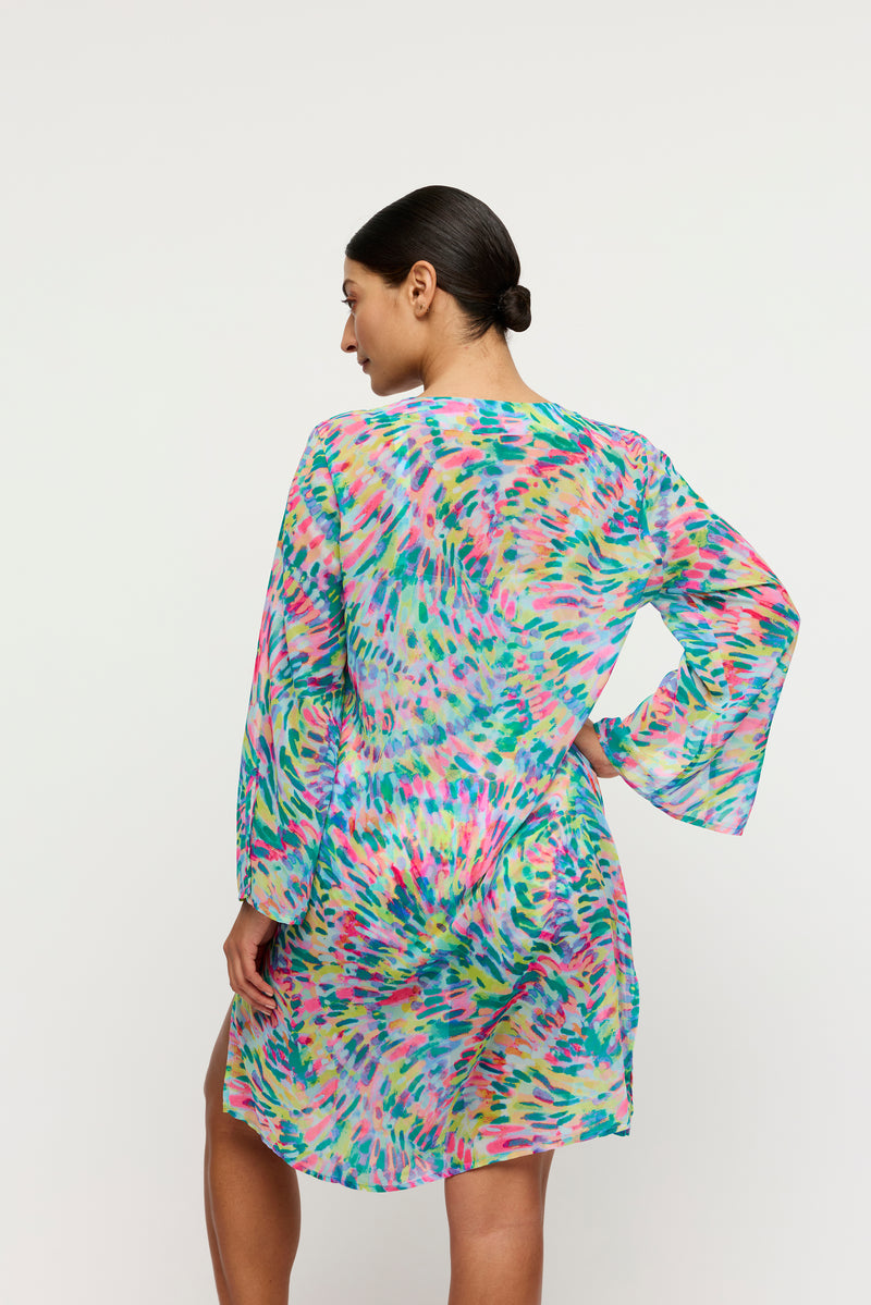 Woman wearing a colorful dress with long sleeves on a white background