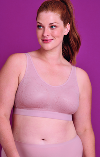 Woman wearing a light purple wireless bra against a purple background