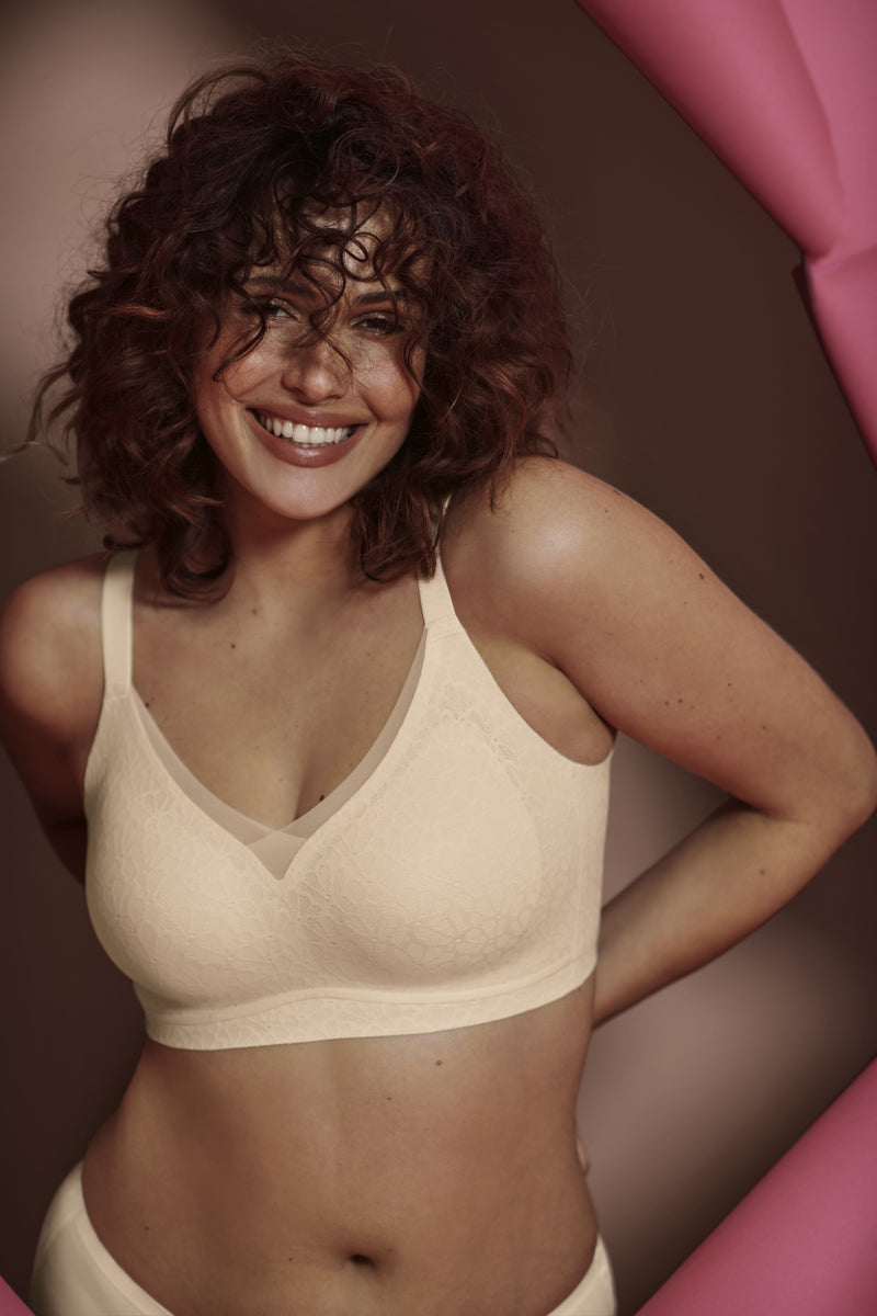 Woman wearing a beige bra against a pink and brown background